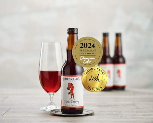 Paynter's Mon hCerry cider bottle with a glass of cider and gold awards on a light background